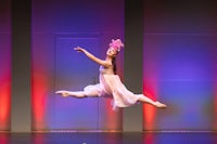 a girl in a pink dress is jumping in the air