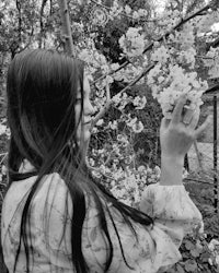 a black and white photo of a girl holding a flower