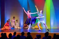 two dancers performing on stage in front of colorful lights